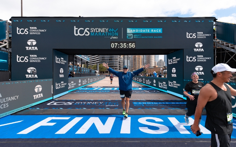 Runner happily crosses finish line at Sydney Marathon.