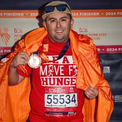 Team Move For Hunger runner, Matt, holding medal after NYC marathon.